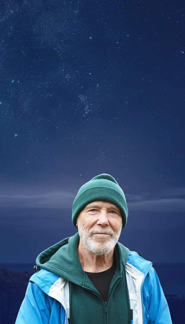 Image of man standing in front of dark, starry sky landscape